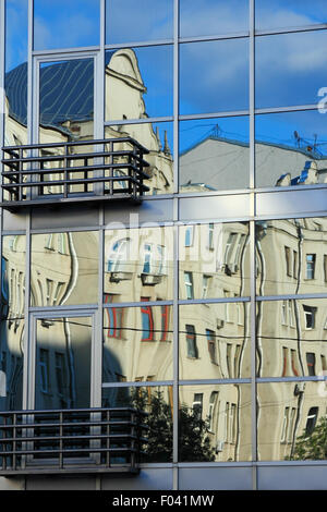 Un edificio moderno riflette con le sue finestre vecchio appartamento edifici del. Foto Stock