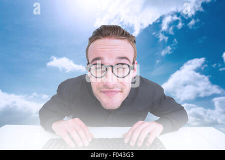 Immagine composita di imprenditore sorridente digitando sulla tastiera a scrivania Foto Stock