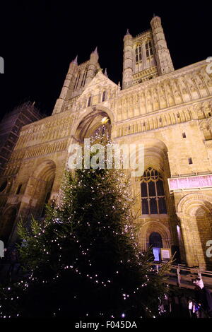 Un albero di Natale al di fuori dell'entrata principale di un illuminato Cattedrale di Lincoln durante la Città mercatino di Natale, England Regno Unito Foto Stock