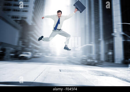 Immagine composita di allegro jumping imprenditore con la sua valigia Foto Stock