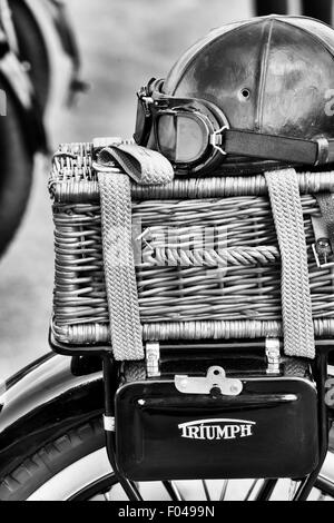 Vecchia pelle vintage casco e occhiali e cesto di vimini su un vintage Triumph motocicletta. In bianco e nero Foto Stock