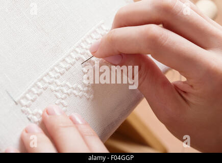 La donna le mani facendo il punto croce. Una chiusura del ricamo. Foto Stock