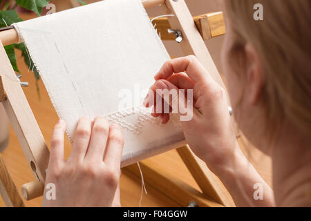 La donna le mani facendo il punto croce. Una chiusura del ricamo. Foto Stock