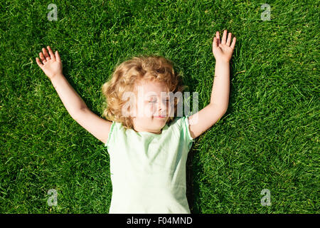 Dreaming adorabile bambina giacente su erba, vista dall'alto Foto Stock