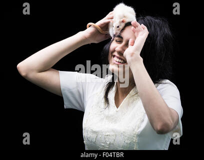 Sorridente latina adolescente con ratto sul suo capo Foto Stock