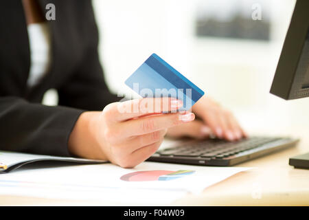 Business donna tenendo la carta di credito in mano e immettendo il codice di protezione utilizzando la tastiera del notebook Foto Stock