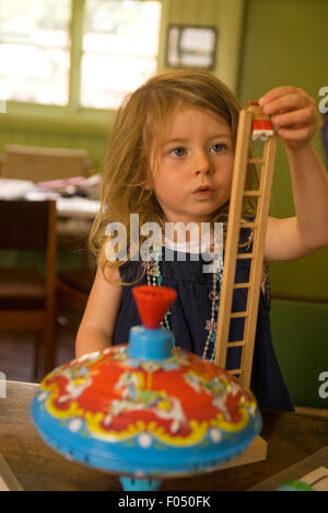 3 anno vecchia ragazza assorbiti nel giocare con giocattoli tradizionali in legno in corrispondenza di un evento del patrimonio, la vita rurale centro, Tilford, Surrey, Regno Unito. Foto Stock