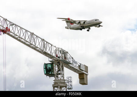 Cityjet Dornier 328-110 in atterraggio a City Airport London dietro di gru a torre galeoni a raggiungere lo sviluppo, Docklands Foto Stock