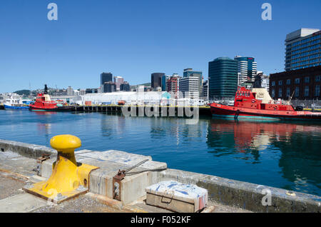 Rimorchiatore rosso imbarcazioni al porto, edifici per uffici e il CBD dietro, Wellington, Isola del nord, Nuova Zelanda Foto Stock