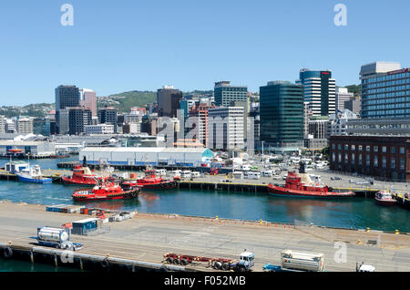 Rimorchiatore rosso imbarcazioni al porto, edifici per uffici e il CBD dietro, Wellington, Isola del nord, Nuova Zelanda Foto Stock