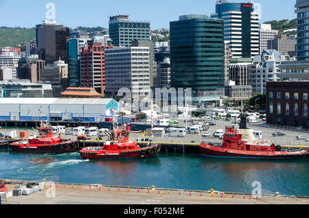 Rimorchiatore rosso imbarcazioni al porto, edifici per uffici e il CBD dietro, Wellington, Isola del nord, Nuova Zelanda Foto Stock