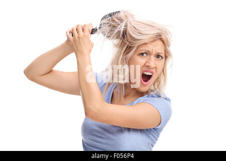 Studio shot di turbare la donna con i capelli aggrovigliati in una spazzola per capelli isolati su sfondo bianco Foto Stock