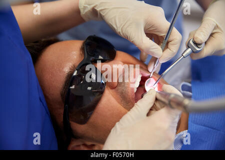 Dentista mani trattamento paziente di sesso maschile di denti Foto Stock