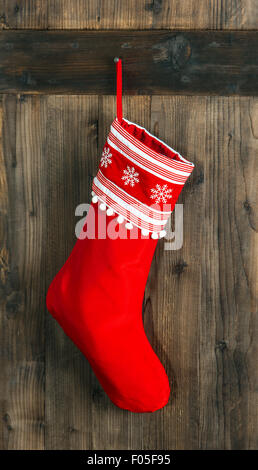 Calza di Natale. Calza rossa con i fiocchi di neve per Santa regali appesi sopra in legno rustico sfondo. Vacanze a decorazione Foto Stock