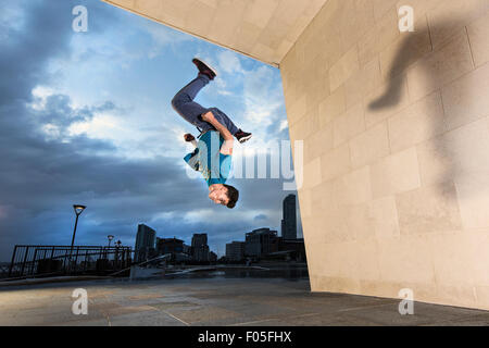 Un freerunner capovolge su un muro. Foto Stock