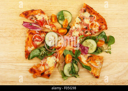 Fette di pizza e insalate condite su una tavola di legno Foto Stock