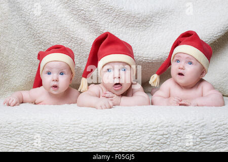 I neonati con cappelli di Babbo Natale su sfondo lucido Foto Stock