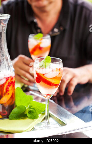L'uomo bianco potabile sangria. La sangria bianca con frutti e bacche. Foto Stock
