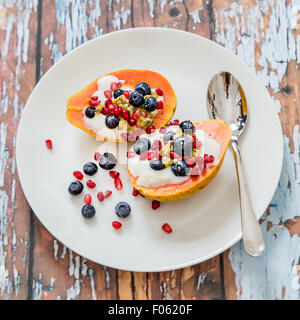 La papaia con soia naturale yogurt e frutti di bosco freschi, leggera e sana colazione, papaia, mirtilli, frutto della passione, melograno Foto Stock