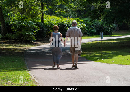 Una coppia senior tenendo le mani a piedi attraverso il parco ovest su una giornata d'estate in Wolverhampton West Midlands, Regno Unito Foto Stock