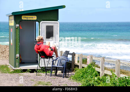 North Cornwall - Polzeath scogliera lifeguard post - lifeguard a proprio agio ma su watch - blu/verde mare - bianco breakers - surfers Foto Stock