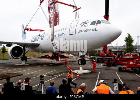 Un piano di Airbus tipo A 300 viene sollevato da un60-metro-alta gru su di un area di parcheggio all'aeroporto di Colonia-Bonn, Germania, 8 agosto 2015. L'Airbus A300 ZERO-G è stato usato fino al 2014 dalla nazionale tedesco di ricerca aeronautica e spaziale centro 'DLR" a prova di gravità zero, in autunno sarà utilizzato come un aeroplano interattivo nel museo. Foto: Horst Galuschka - nessun filo SERVICE - Foto Stock