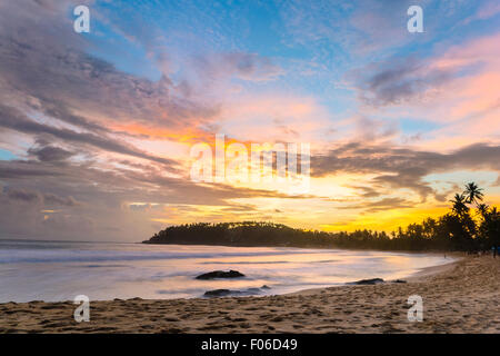 Golden tramonto sulla spiaggia deserta con colorati sky e scenic cloudscape durante il monsone di tempo. Complesso turistico di Mirissa, Sri Lanka, Foto Stock