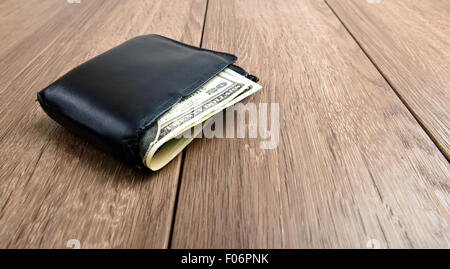 Vecchio portafoglio con banconote di dollari su sfondo di legno Foto Stock