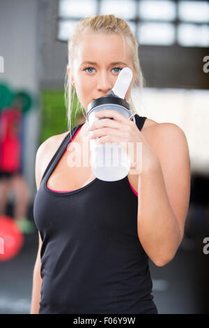 Donna attraente acqua potabile ad una palestra per il fitness Foto Stock