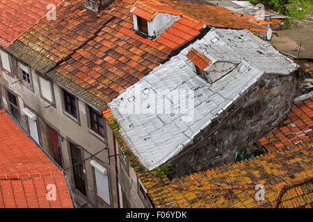 Case tradizionali con tetti di tegole rosse, uno di essi coperto con un foglio di alluminio isolamento Foto Stock