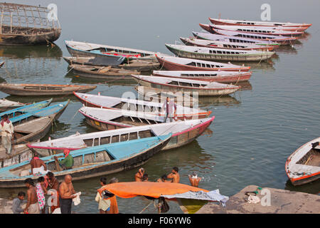 Indù e bagnanti ormeggiate imbarcazioni da diporto sulle rive del fiume sacro Gange a Varanasi nel tardo pomeriggio Foto Stock