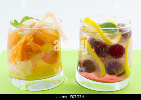 Pesca e lampone succhi di frutta con fette di frutta in un storto vetro su sfondo verde. Bevande fredde Foto Stock