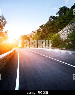 Strada asfaltata nel bosco estivi al tramonto. Montagne di Crimea. Foto Stock