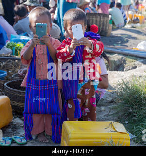 Due bambini birmani utilizzare telefoni cellulari a Nam Pan 5 giorni di mercato sul Lago Inle nello Stato di Shan, Myanmar Foto Stock