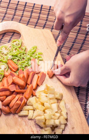 Preparazione di una stir fry di legumi stufati e salsiccia Foto Stock