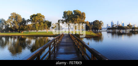 Una passerella su un lago nel Sir James Mitchell Park, South Perth, con la città di Perth in distanza. Western Australia, Australia. Foto Stock