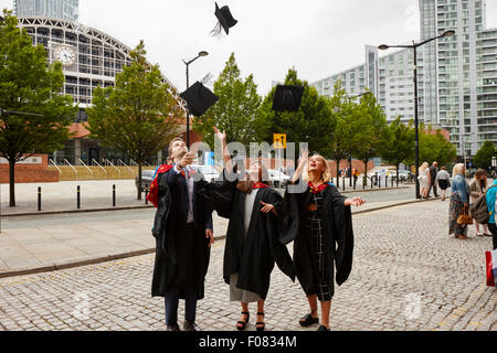 I laureati di gettare la scheda di mortaio cappelli in aria dopo la cerimonia di laurea in Manchester Inghilterra England Regno Unito Foto Stock