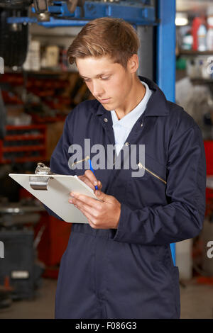 Apprendista meccanico lavora in negozio di riparazioni auto Foto Stock