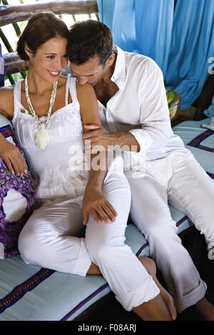 Amare giovane in abito bianco, uomo kissing alle spalle della donna sorridente Foto Stock