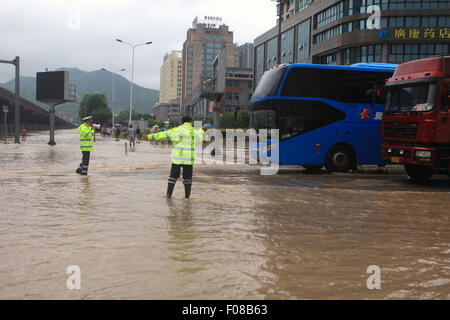 Taizhou, cinese della Provincia di Zhejiang. 10 Ago, 2015. Poliziotti del traffico traffico diretto a Daxi sezione del National Highway 104 in Wenling, est della Cina di Provincia dello Zhejiang, il 10 agosto 2015. A causa delle pesanti piogge causate dal tifone Soudelor dal 9 agosto al 10 agosto, sezione locale del National Highway 104 era saturo di acqua e il traffico è stato interrotto. Il traffico è stato ripreso lunedì mattina. Credito: Zhou Xuejun/Xinhua/Alamy Live News Foto Stock