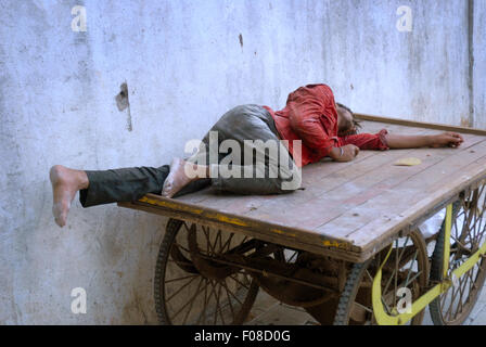 Uomo indiano di dormire su un carrello di legno, Mumbai, India. Foto Stock