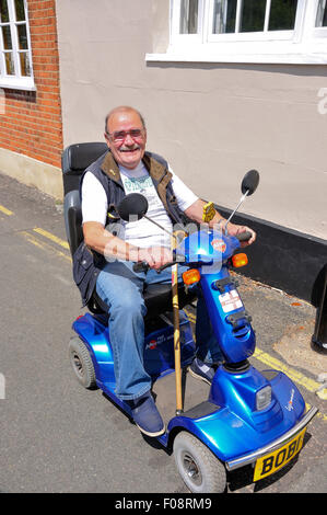 Uomo sorridente sulla mobilità scooter, la terrazza, Wokingham, Berkshire, Inghilterra, Regno Unito Foto Stock