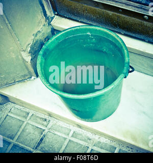 Antichi verde secchio in plastica pieno di acqua. Foto Stock