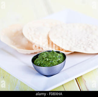 Un mucchio di poppadoms con una ciotola di chutney corriander Foto Stock