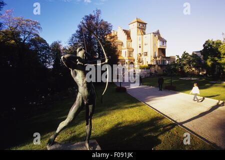 Statua tenendo la prua e la freccia vicino al castello in pietra, Salisburgo, Austria Foto Stock