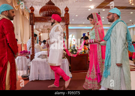 La religione sikh sposa e lo sposo a piedi attorno al libro sacro alla cerimonia di matrimonio a Brent Cross Gurdwara Foto Stock