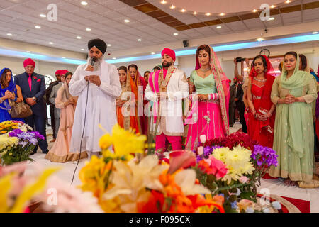 Sacerdote con la sposa e lo sposo a Sikh cerimonia di nozze in Brent Gurdwara Londra Foto Stock