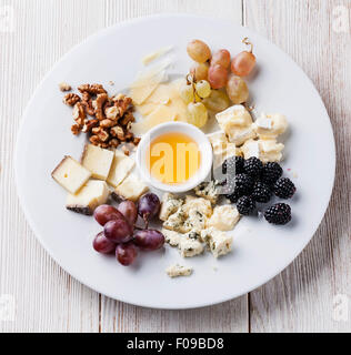 Il piatto di formaggi assortimento di vari tipi di formaggio e miele sulla piastra bianca Foto Stock