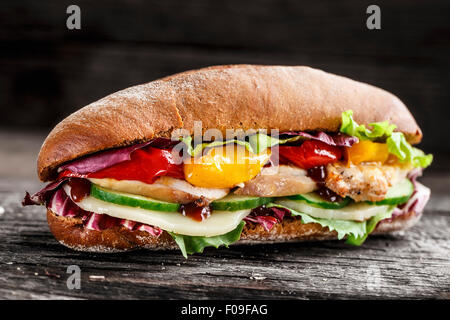 Sandwich di pollo, formaggio e verdure su un sfondo rustico Foto Stock