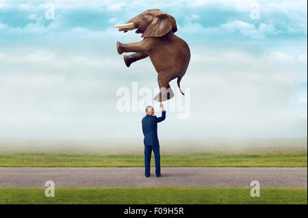 La resistenza di affari concetto imprenditore tenendo un elefante con un dito Foto Stock